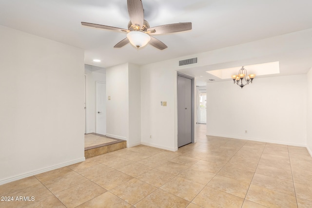 tiled empty room featuring ceiling fan with notable chandelier