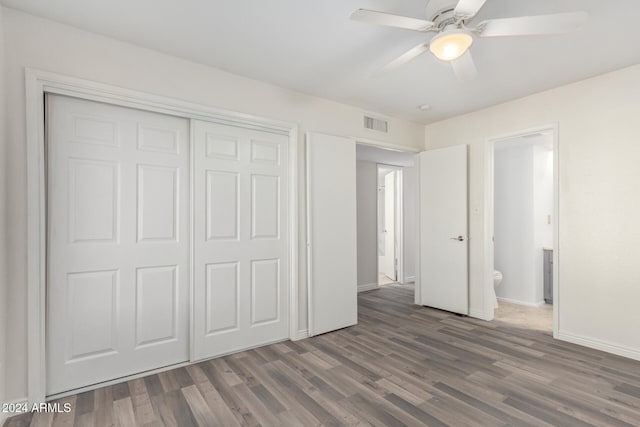 unfurnished bedroom with connected bathroom, ceiling fan, a closet, and dark wood-type flooring