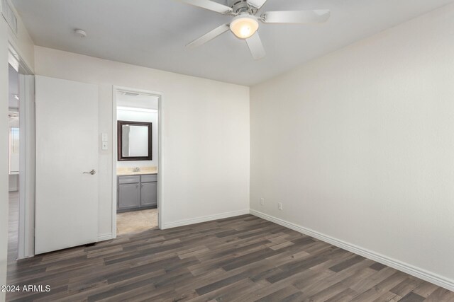 unfurnished bedroom with connected bathroom, ceiling fan, dark wood-type flooring, and sink