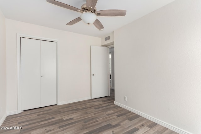 unfurnished bedroom featuring a closet, dark wood-type flooring, and ceiling fan