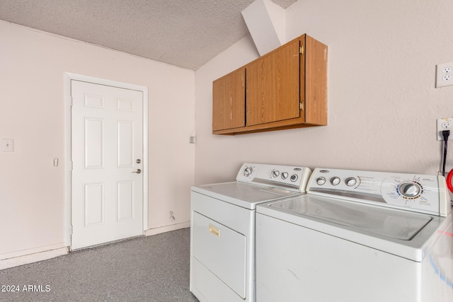 washroom with cabinets, a textured ceiling, and washing machine and dryer