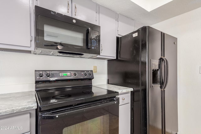 kitchen with black appliances, tile patterned flooring, white cabinets, and a textured ceiling