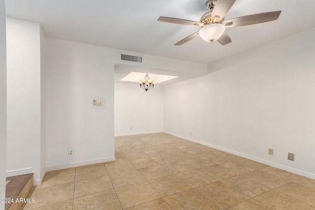 tiled spare room with ceiling fan with notable chandelier