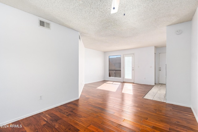 empty room with a textured ceiling and hardwood / wood-style flooring