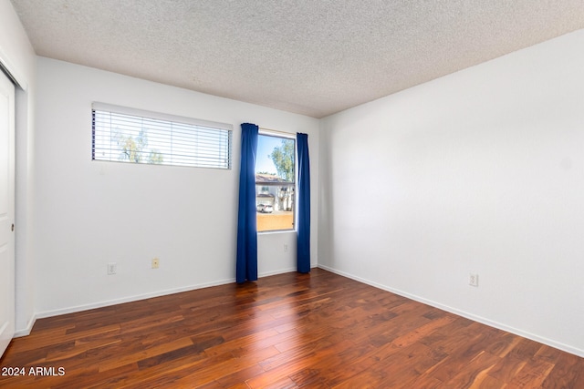 empty room with dark hardwood / wood-style floors and a textured ceiling