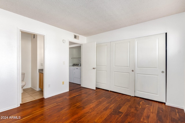 unfurnished bedroom featuring a closet, washer and dryer, connected bathroom, and dark hardwood / wood-style floors