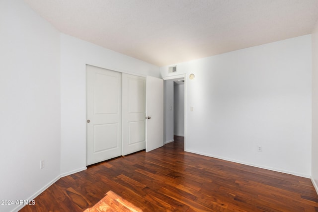 unfurnished bedroom with a closet and dark hardwood / wood-style floors