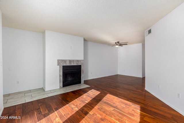 unfurnished living room with ceiling fan, hardwood / wood-style floors, a textured ceiling, and a fireplace