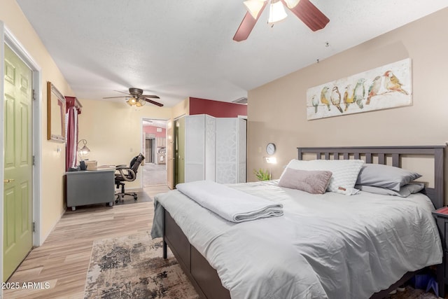 bedroom featuring a ceiling fan, light wood-style flooring, visible vents, and a textured ceiling