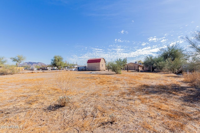 view of yard featuring a rural view, an outdoor structure, and a mountain view