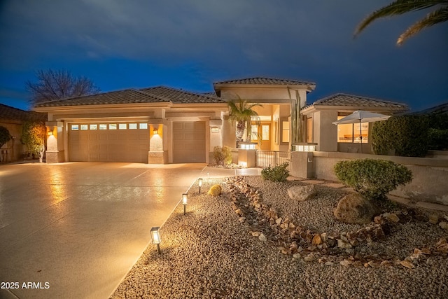 view of front of home with stucco siding, concrete driveway, an attached garage, and a tile roof