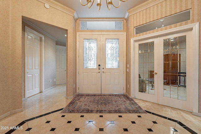 foyer entrance featuring french doors, crown molding, light tile patterned floors, baseboards, and a chandelier