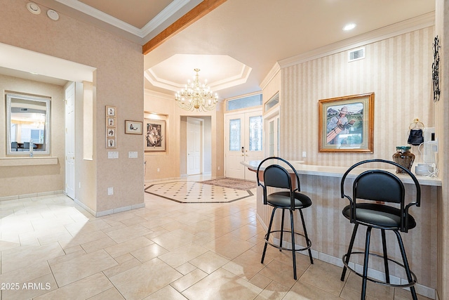 entrance foyer with baseboards, visible vents, a chandelier, and ornamental molding