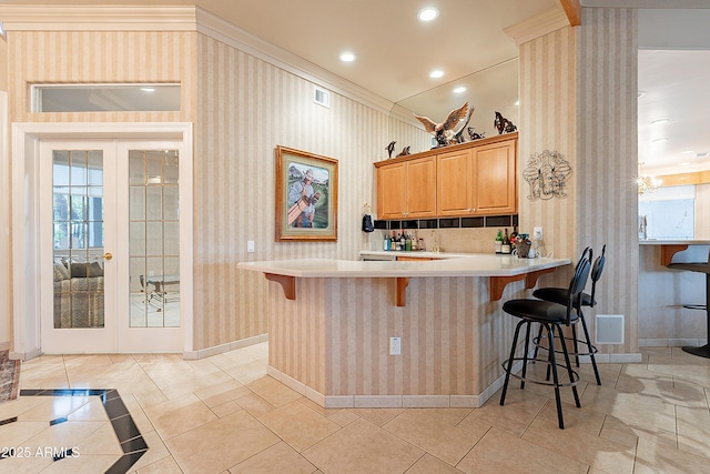 kitchen with french doors, a kitchen breakfast bar, light countertops, and wallpapered walls