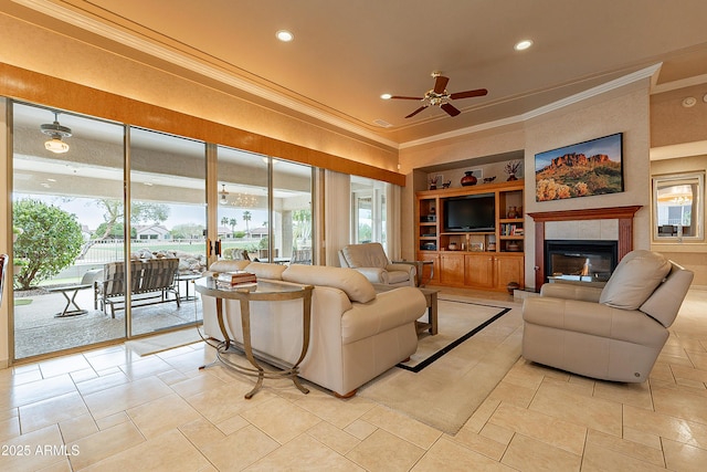 living room featuring built in shelves, crown molding, ceiling fan, recessed lighting, and a tile fireplace