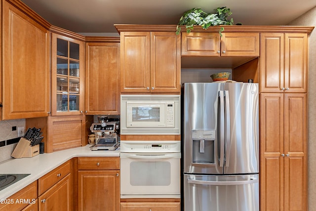 kitchen with glass insert cabinets, decorative backsplash, white appliances, and light countertops