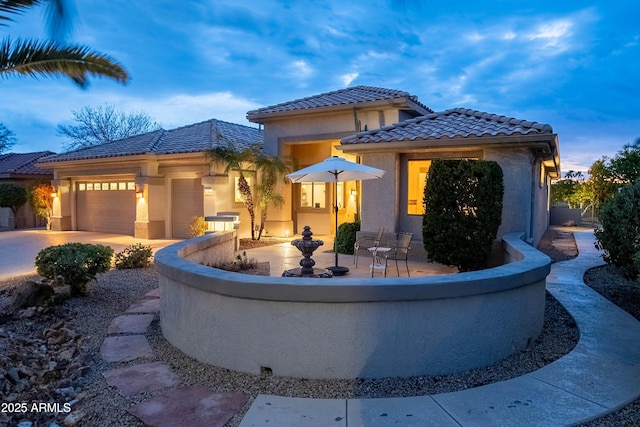 view of front facade featuring a tile roof, an attached garage, driveway, and stucco siding