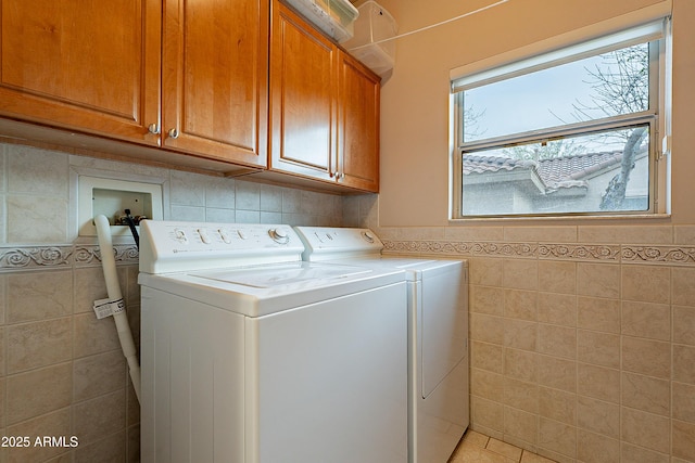 laundry room with cabinet space, separate washer and dryer, tile walls, and wainscoting