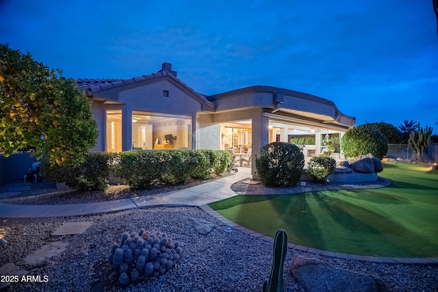 rear view of property with a tile roof and stucco siding