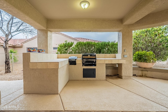 view of patio featuring exterior kitchen, fence, and a grill