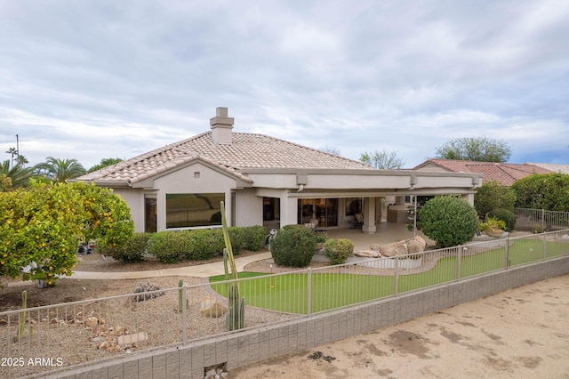 rear view of property featuring a fenced backyard, a chimney, stucco siding, a tile roof, and a patio area