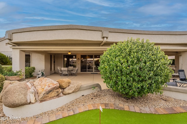 back of property with stucco siding and a patio