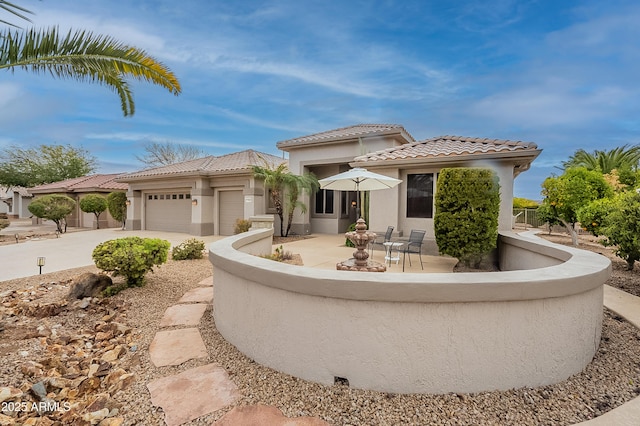 view of front of property with concrete driveway, a tiled roof, an attached garage, and stucco siding