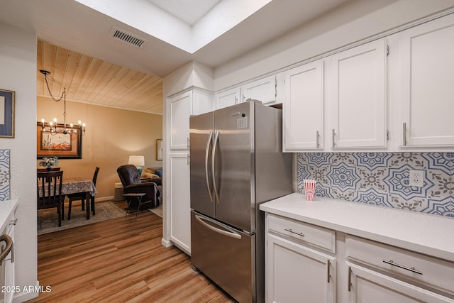 kitchen featuring a chandelier, hanging light fixtures, light wood-type flooring, white cabinetry, and stainless steel refrigerator