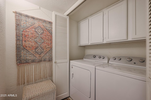 laundry area with a textured ceiling, cabinets, and washing machine and clothes dryer