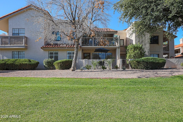 rear view of property featuring a balcony and a yard