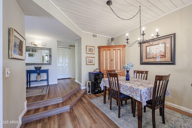 dining area featuring a notable chandelier, dark wood-type flooring, wooden ceiling, and crown molding