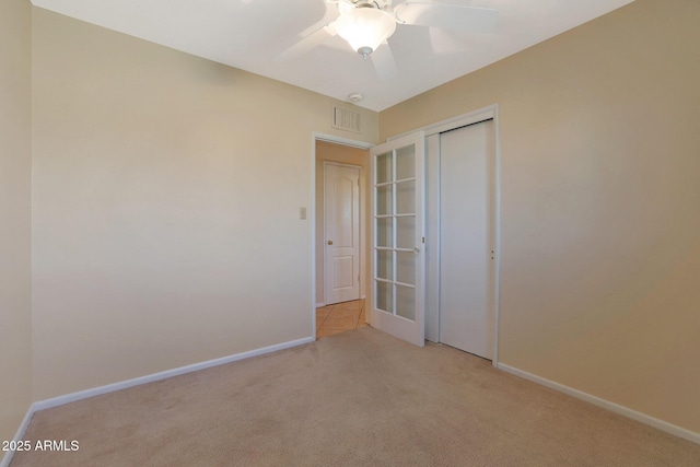 unfurnished bedroom featuring ceiling fan, light colored carpet, and a closet