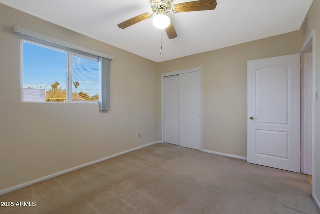 unfurnished bedroom featuring ceiling fan, light carpet, and a closet