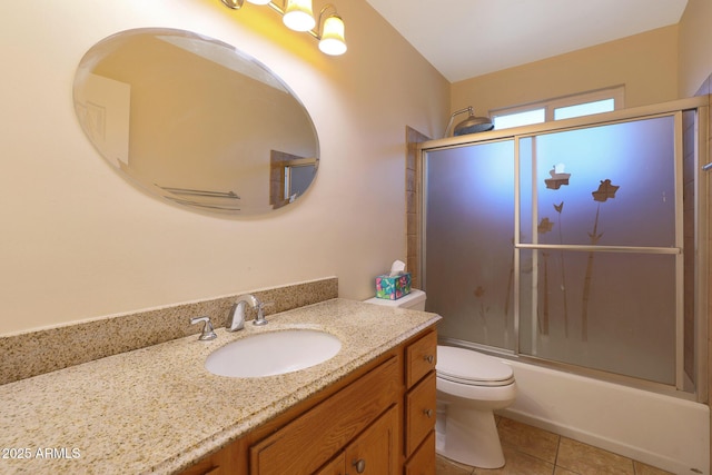 full bathroom with tile patterned floors, vanity, bath / shower combo with glass door, and toilet