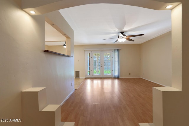 empty room featuring ceiling fan, french doors, and light hardwood / wood-style flooring