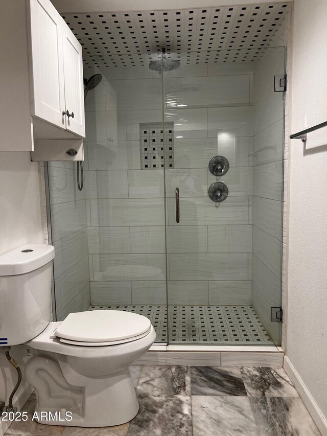 full bathroom with marble finish floor, a shower stall, toilet, and baseboards