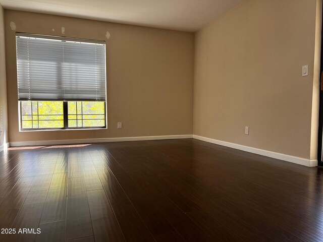 empty room with baseboards and dark wood-style floors