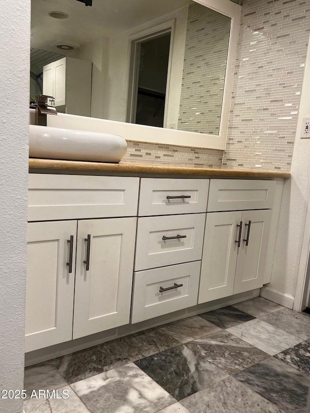 bathroom featuring double vanity, baseboards, decorative backsplash, and a sink