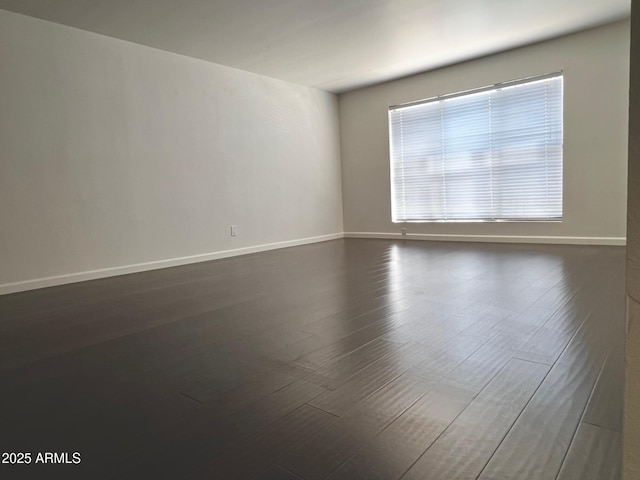 empty room featuring baseboards and dark wood-style floors