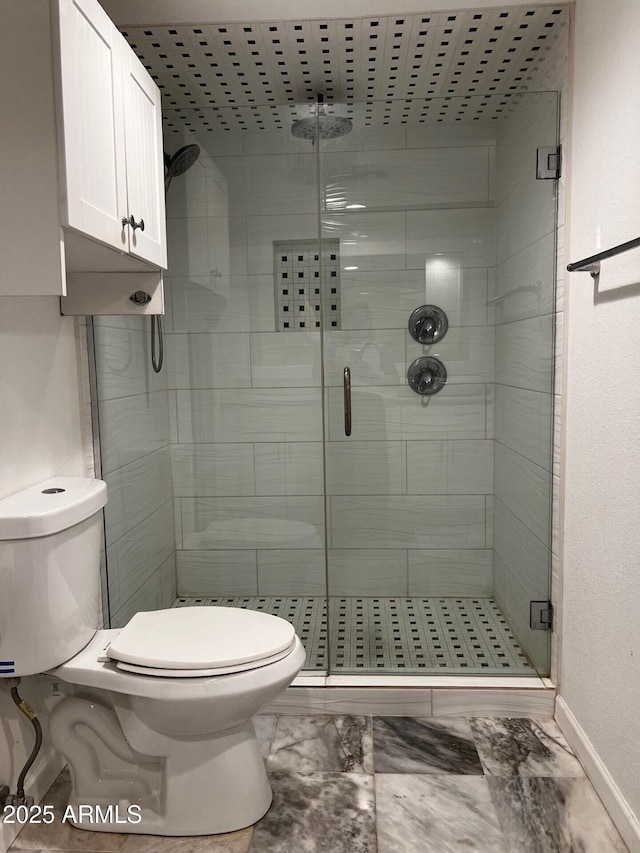 full bathroom with marble finish floor, a shower stall, toilet, and baseboards
