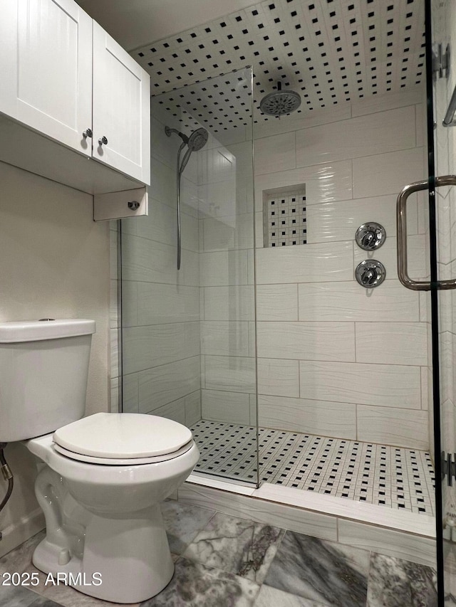 bathroom with marble finish floor, a shower stall, and toilet