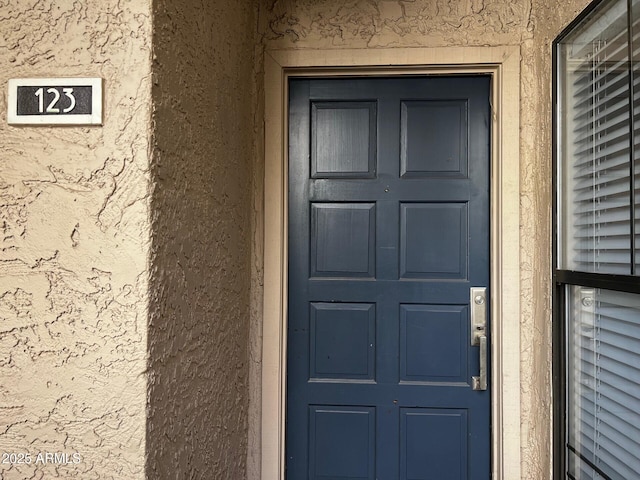 entrance to property featuring stucco siding