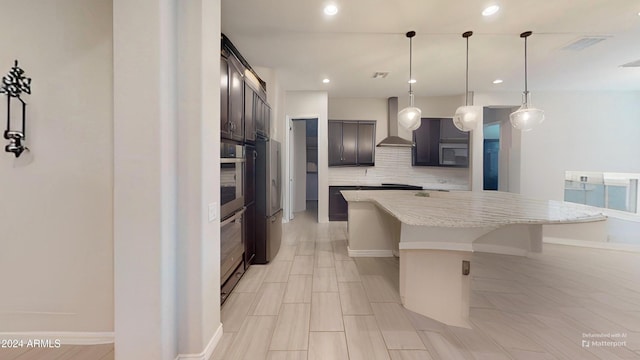 kitchen featuring appliances with stainless steel finishes, a kitchen island, decorative light fixtures, light stone countertops, and wall chimney exhaust hood