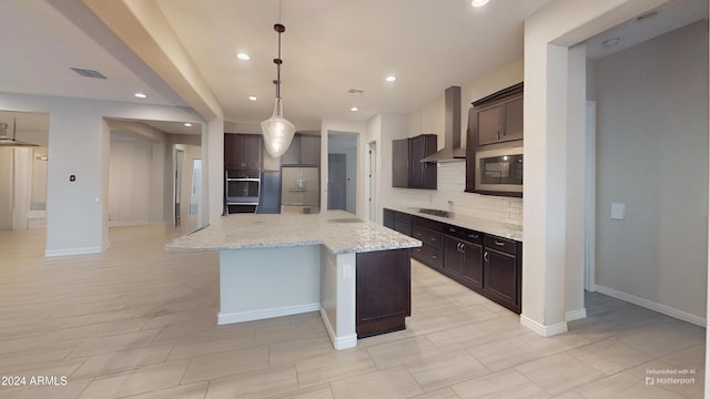 kitchen featuring wall chimney range hood, a kitchen island with sink, backsplash, black appliances, and decorative light fixtures