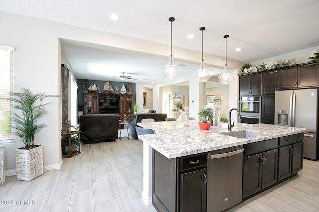 kitchen with dark brown cabinetry, sink, hanging light fixtures, a center island with sink, and stainless steel appliances