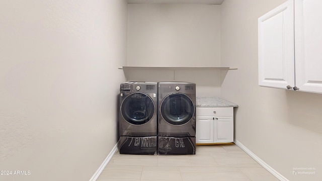 washroom featuring cabinets, washing machine and clothes dryer, and light tile patterned floors