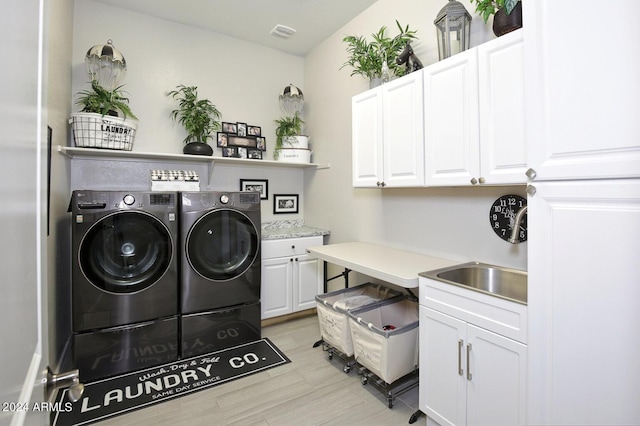 clothes washing area with cabinets, washing machine and dryer, and sink