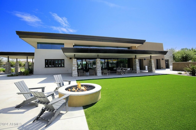 rear view of house with an outdoor fire pit, a yard, and a patio