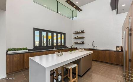 bar featuring light tile patterned flooring, sink, and a high ceiling