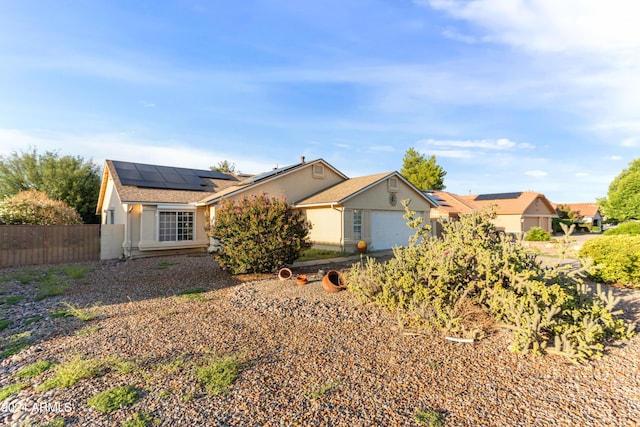 single story home with a garage and solar panels